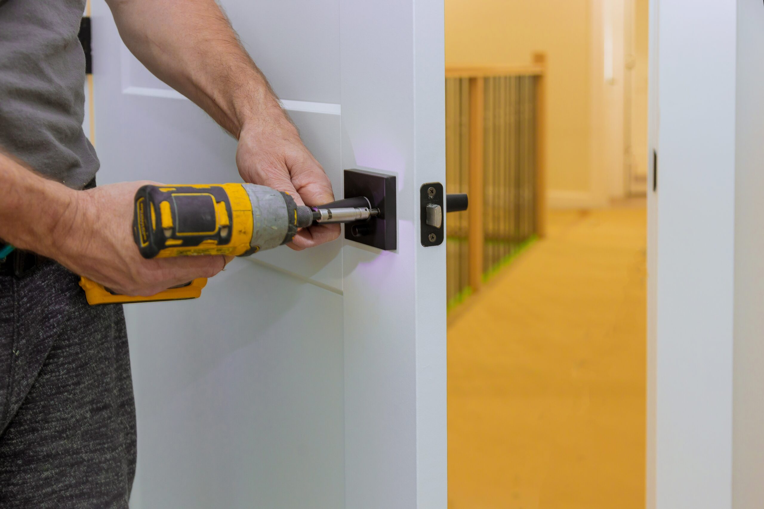 Handyman installing the door lock in the room with screwdriver, Close-up of new a house on the open door