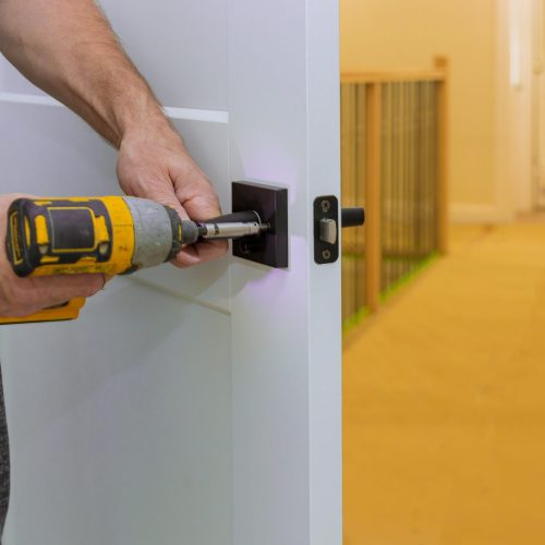 Handyman installing the door lock in the room with screwdriver, Close-up of new a house on the open door